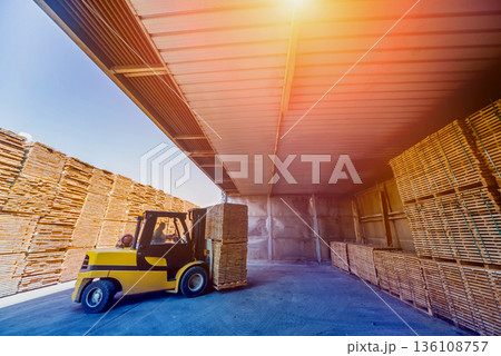 Forklift loader load lumber into a dry kiln. Wood drying in containers. Forklift loader load lumber into a dry kiln. Wood drying in containers. 136108757