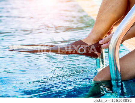 Young athletic man wearing flippers by the pool Young athletic man wearing flippers by the pool 136108856