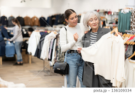 Elderly and young women choosing coat in store 136109334