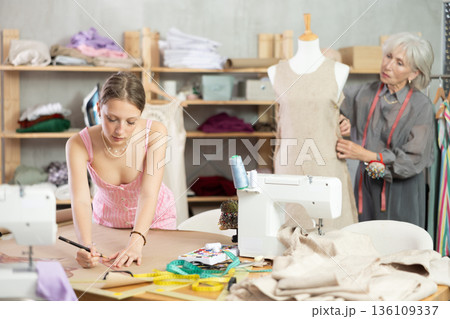Woman tailor drawing a sketch of clothes on brown paper Woman tailor drawing a sketch of clothes on brown paper 136109337