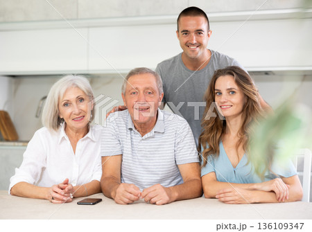 Family of four sitting in kitchen 136109347