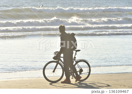 夕方の片瀬西浜海岸の砂浜で自転車を引く男性 夕方の片瀬西浜海岸の砂浜で自転車を引く男性 136109467
