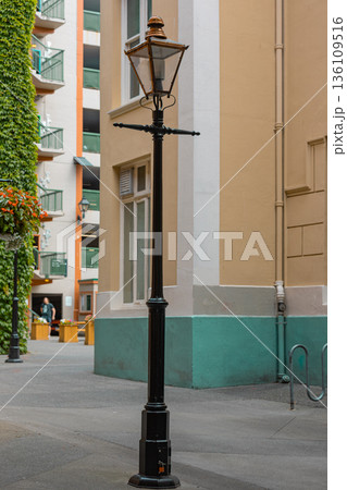 Vintage Victorian era iron street lamp in the background of buildings of the city. 136109516