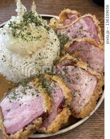 Crispy tonkatsu, a Japanese-style breaded and deep-fried pork cutlet, served with shredded cabbage and drizzled with savory sauce. A delightful balance of crunchy texture and juicy meat. 136109656