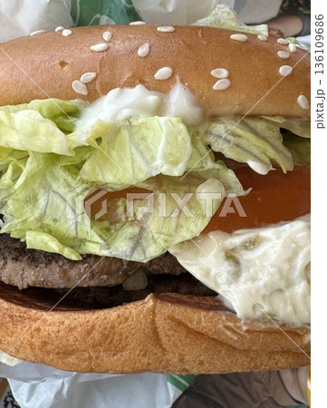 A mouthwatering burger with a juicy patty, fresh lettuce, tomato, and melted cheese, all nestled in a soft bun. Perfect for food photography, showcasing the indulgence of classic comfort food. 136109686