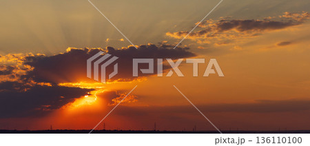 Dramatic sunset sky with sun rays and clouds 136110100