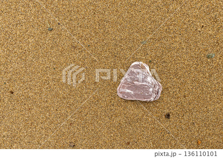 Single stone resting on sandy beach surface 136110101