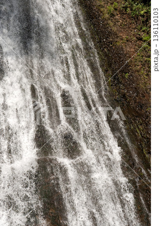 Waterfall flowing over dark rocky cliff Waterfall flowing over dark rocky cliff 136110103