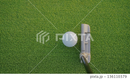 Golf clubs and balls on a green lawn in a beautiful golf course with morning sunshine. 136110379