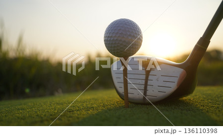 Golf clubs and balls on a green lawn in a beautiful golf course with morning sunshine. 136110398