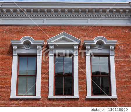 Details of three arched windows in classic style on a brick wall of the house 136110969
