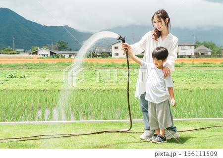 庭の芝生に水やりをする男の子と家族,ファミリー(マイホーム,庭,エクステリア) 庭の芝生に水やりをする男の子と家族,ファミリー(マイホーム,庭,エクステリア) 136111509