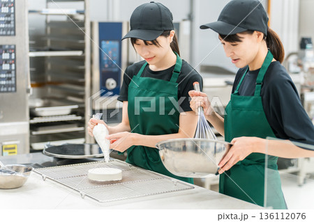 洋菓子店,ベーカリーの厨房でケーキを作る調理スタッフの女性 136112076