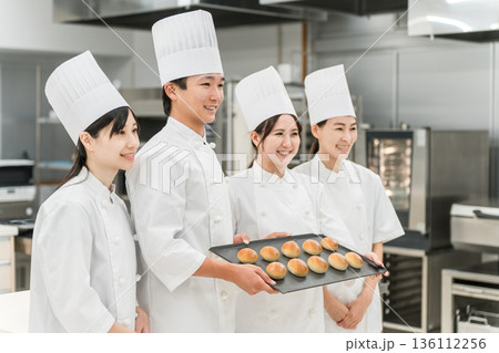 厨房・キッチンに立つコックコート姿の調理師・シェフ・コックの男女 136112256