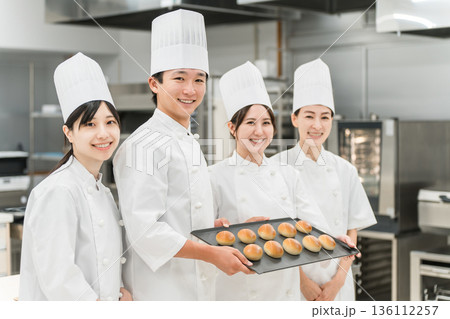 厨房・キッチンに立つコックコート姿の調理師・シェフ・コックの男女 136112257