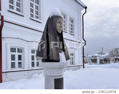 A young, happy blonde girl is traveling in winter, sitting on a train, looking out the window and drinking hot tea 136112678