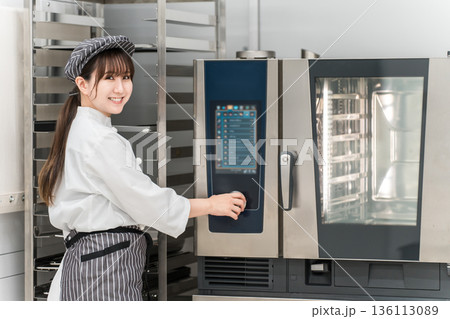 業務用オーブンを取り扱う女性調理スタッフ 136113089