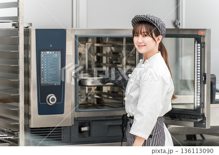 業務用オーブンを取り扱う女性調理スタッフ 136113090