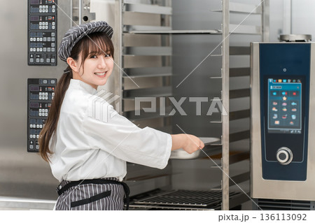 業務用オーブンを取り扱う女性調理スタッフ 136113092