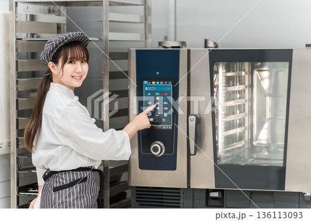 業務用オーブンを取り扱う女性調理スタッフ 業務用オーブンを取り扱う女性調理スタッフ 136113093