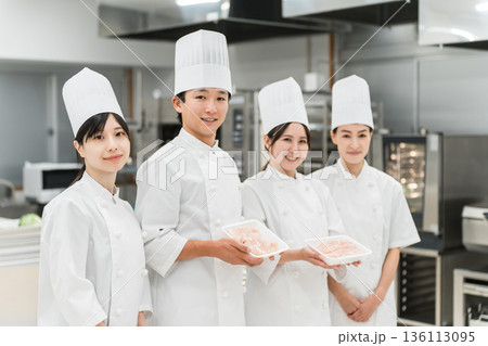 鶏肉を持つコックコート姿のシェフ・コック・調理師の男女 136113095