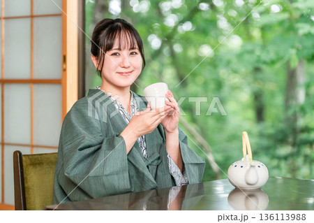 旅館の和室でお茶を飲む浴衣姿の若いアジア人女性 旅館の和室でお茶を飲む浴衣姿の若いアジア人女性 136113988