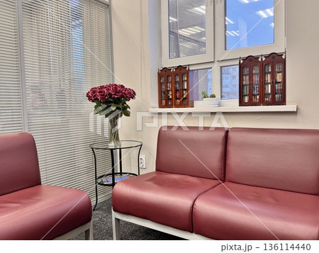 A waiting area with red sofas and a coffee table with flowers at the notary 136114440