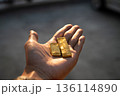 Hand holding real gold bullion bars in warm sunset light. Financial growth, wealth accumulation, and physical gold asset investment. Hand holding real gold bullion bars in warm sunset light. Financial growth, wealth accumulation, and physical gold asset investment. 136114890