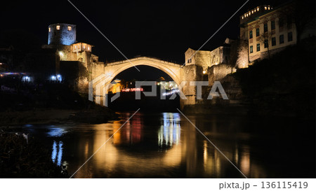 Illuminated Stone Bridge Reflected in River at Night 136115419