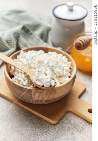 Cottage cheese in wooden bowl with honey dipper 136115936
