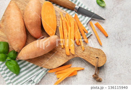 Preparing sweet potato fries on a wooden cutting board Preparing sweet potato fries on a wooden cutting board 136115940