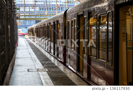 Berlin, germany, august 11, 2023. S-bahn train waits at a berlin platform with another train in the distance, urban transit scene highlighting modern rail infrastructure Berlin, germany, august 11, 2023. S-bahn train waits at a berlin platform with another train in the distance, urban transit scene highlighting modern rail infrastructure 136117930