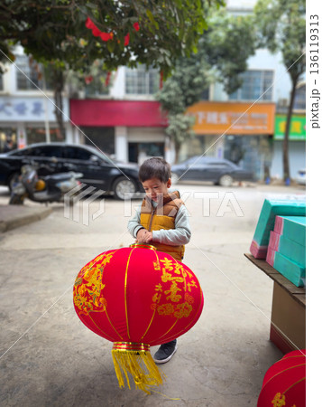 Child Joyfully Holding A Big Red Lantern During Festive Lunar New Year Preparations 136119313