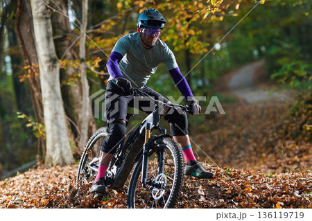 Autumn Forest Mountain Biker In Full Gear Riding Through Fall Leaves On Trail Autumn Forest Mountain Biker In Full Gear Riding Through Fall Leaves On Trail 136119719