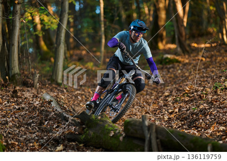 Intense Mountain Biker Navigates Forest Trail Amid Autumn Leaves, Focus, and Adventure Intense Mountain Biker Navigates Forest Trail Amid Autumn Leaves, Focus, and Adventure 136119759