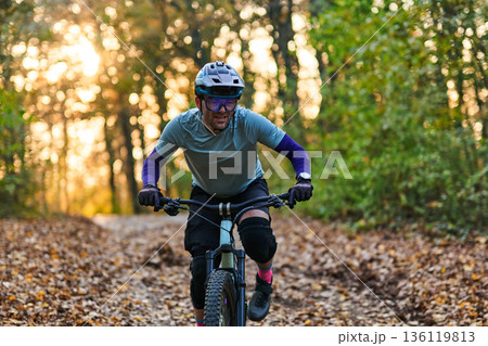 Forest Trail Mountain Biker Riding Fast Through Autumn Leaves During Golden Sunset Light 136119813