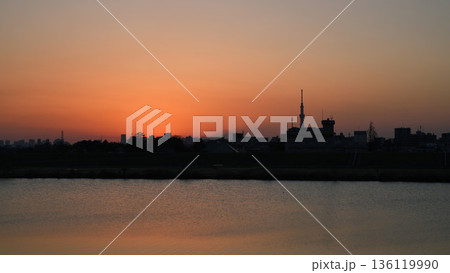 江戸川越しに望む夕焼けの東京スカイツリーと都市シルエット 江戸川越しに望む夕焼けの東京スカイツリーと都市シルエット 136119990