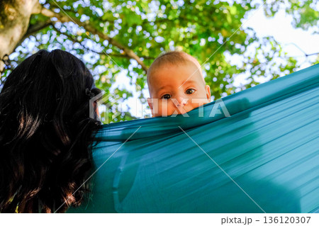 Mother and baby in teal hammock outdoors 136120307