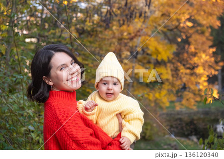Mother and Baby Smiling in Autumn Park Mother and Baby Smiling in Autumn Park 136120340