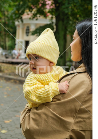 Mother Holding Baby in Yellow Outfit at Park Mother Holding Baby in Yellow Outfit at Park 136120346