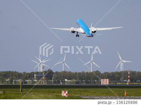 Airplane ascending over wind turbines at Netherlands airport 136120886