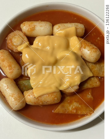 Spicy Korean tteokbokki with chewy rice cakes in a vibrant red sauce, topped with sesame seeds and green onions. A popular street food known for its addictive flavor and satisfying texture. 136122268