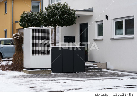 Modern heat pump unit outside a residential house in winter 136122498