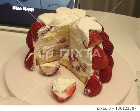 Strawberry cake with soft fluffy layers, topped with fresh strawberries and smooth cream, showcasing vibrant red fruit, delicate textures, and sweet inviting appearance in close-up detail 136122587