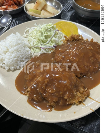 Crispy tonkatsu, a Japanese-style breaded and deep-fried pork cutlet, served with shredded cabbage and drizzled with savory sauce. A delightful balance of crunchy texture and juicy meat. 136122694