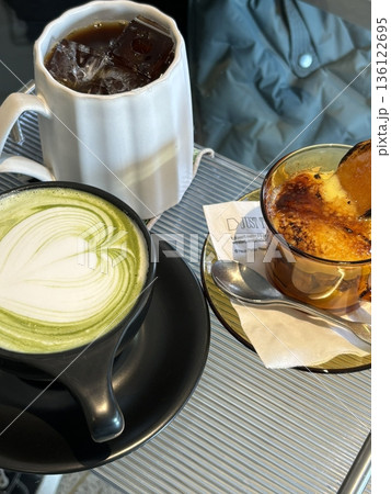 A delightful assortment of desserts displayed in a cozy cafe setting, featuring cakes, pastries, and sweet treats on elegant plates, creating a warm and inviting atmosphere. 136122695