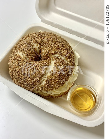 A fresh bagel sandwich filled with layers of smoked salmon, cream cheese, lettuce, and tomato. The golden-brown bagel adds a delightful texture to this classic combination. 136122785