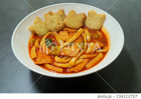 Spicy Korean tteokbokki with chewy rice cakes in a vibrant red sauce, topped with sesame seeds and green onions. A popular street food known for its addictive flavor and satisfying texture. 136122787