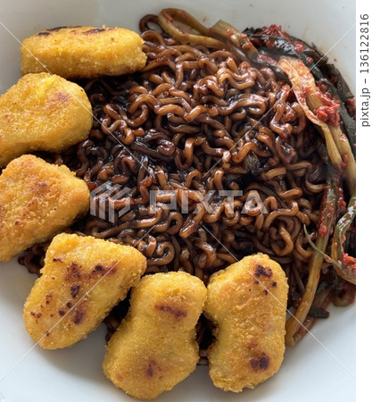 Savory jjapagetti noodles with a rich black bean sauce, topped with green onions and sesame seeds. A comforting Korean favorite that combines depth and flavor in each bite. 136122816