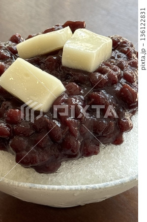 Refreshing patbingsu with fluffy shaved ice, sweet red bean paste, chewy rice cakes, and fresh fruit toppings. A classic Korean dessert, perfect for cooling down on hot days with a delightful taste! 136122831